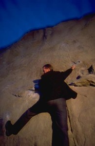 business person climbing rock wall
